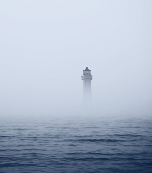 Lighthouse in foggy sea